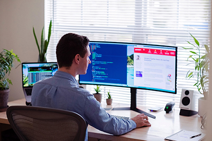 A man working from home in front of a big monitor